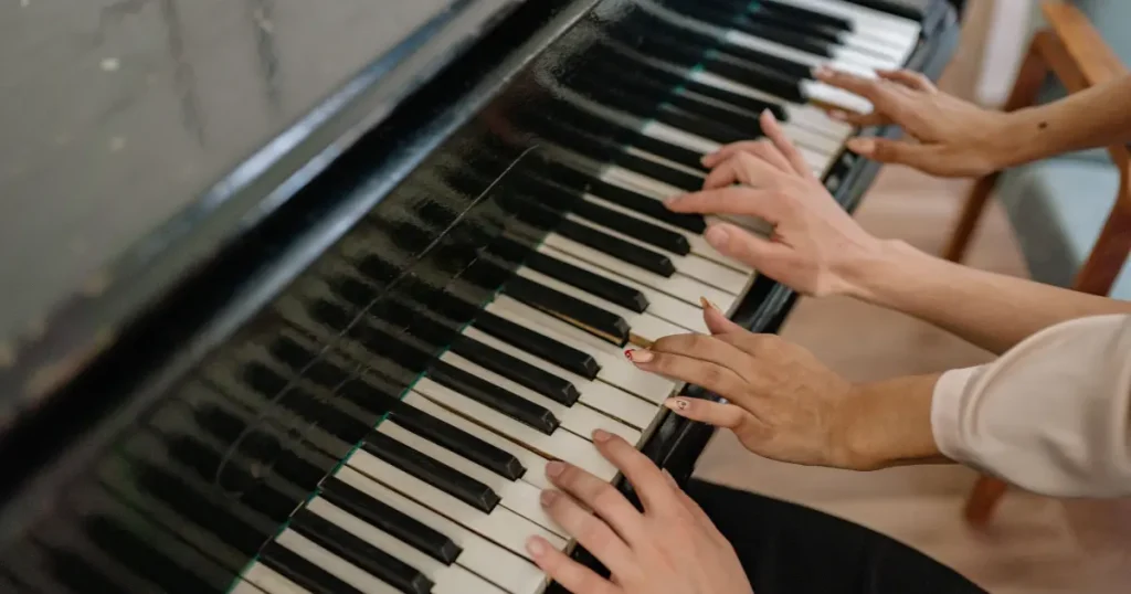 Two people playing a piano duet — illustrative musical entertainment for all-inclusive family resorts east coast.