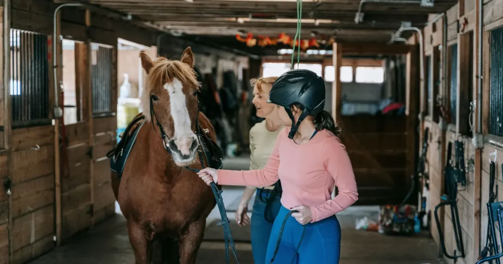 Helmeted rider guiding a horse from a stable — illustrative activity for all-inclusive family resorts on east coast.